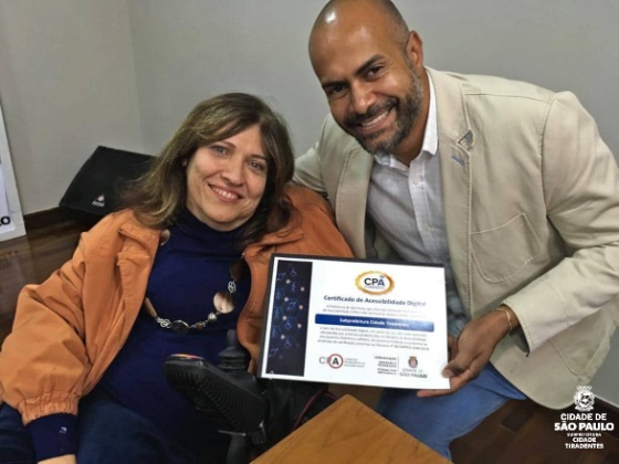 Subprefeito da Cidade Tiradentes junto com o Secretária Silvana Cambiaghi mostrando o certificado do Selo de Acessibilidade Digital